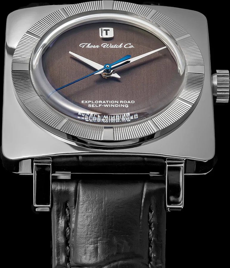Official THORN image of the T016 with a dark gray textured dial in a squared-off steel case on a black strap.